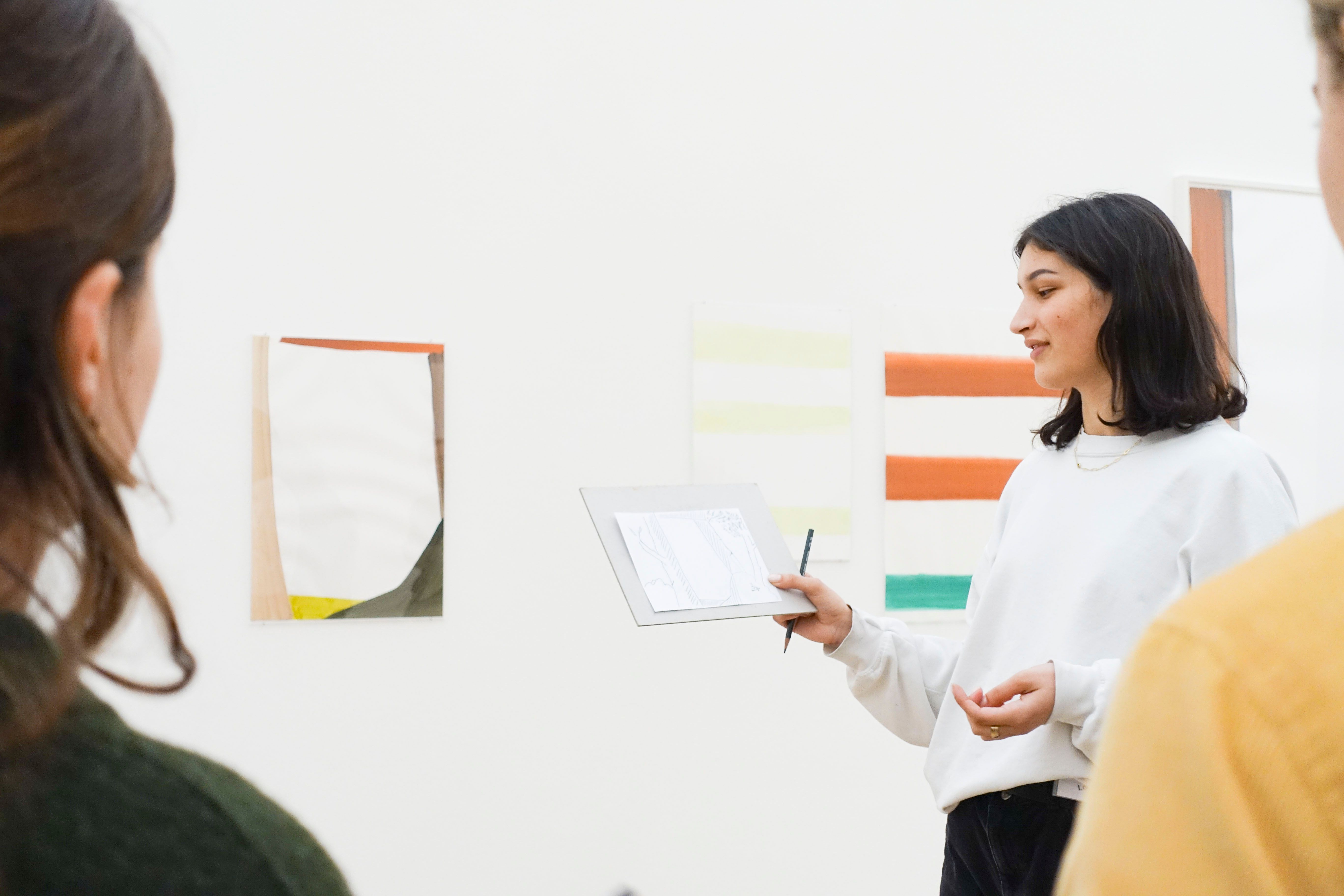 Young people discuss in front of paintings.